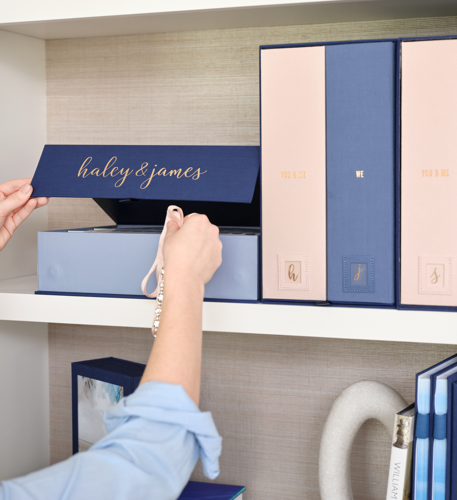 savor wedding boxes sitting on a shelf, hand placing a keepsake inside