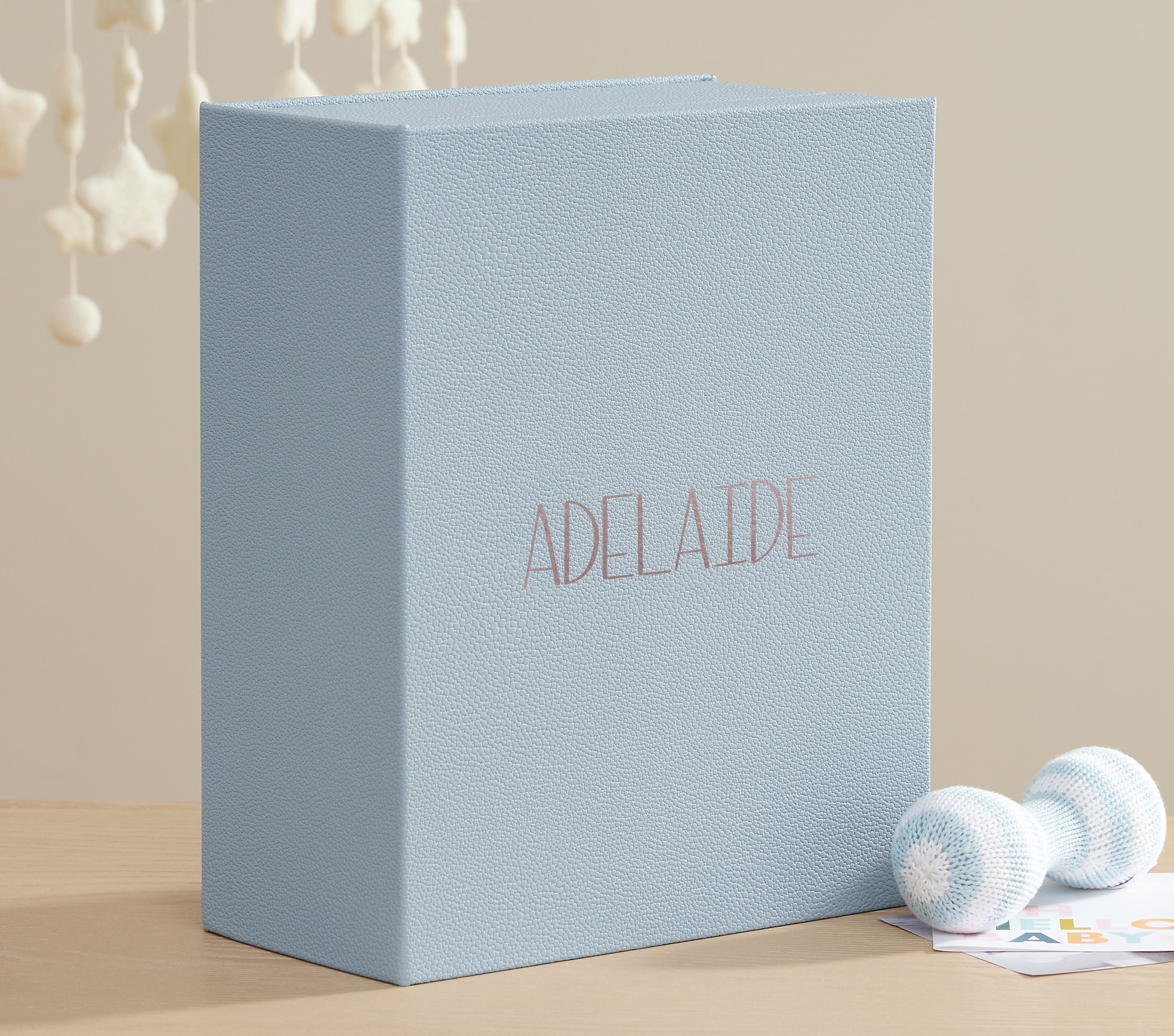 Closed three quarter view of a closed sky shagreen vault personalized with Adelaide with baby props