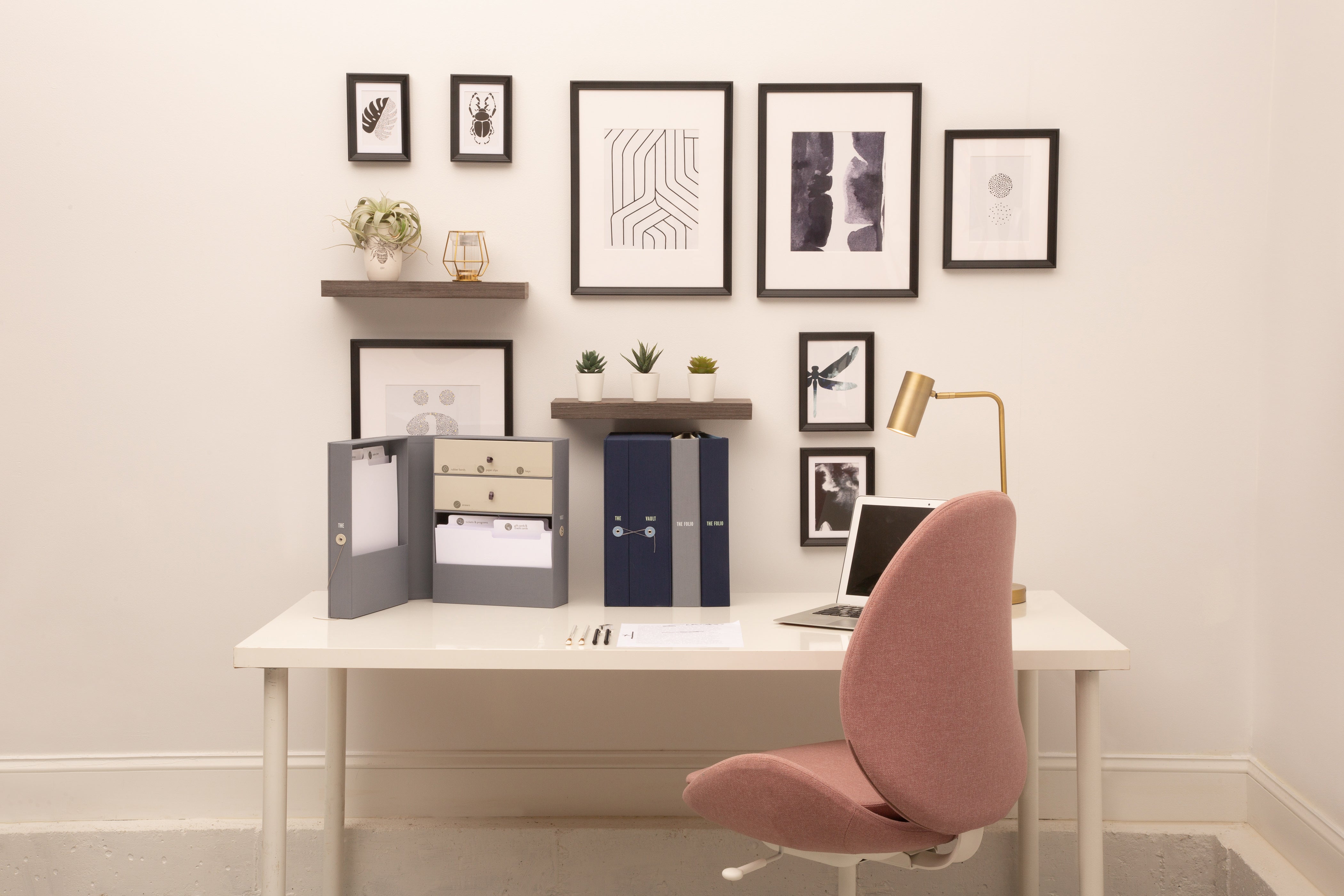 Savor organizers (a keepsake box and a folio) sitting on desk, in front of a wall with frames