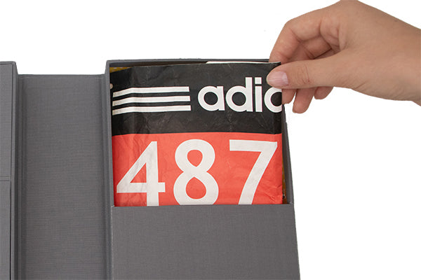 an open slate story box and someone taking an adidas shirt from the inside
