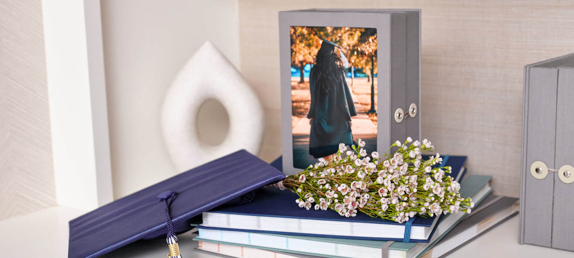 a slate story box with graduation photo on top of three fan folios with props