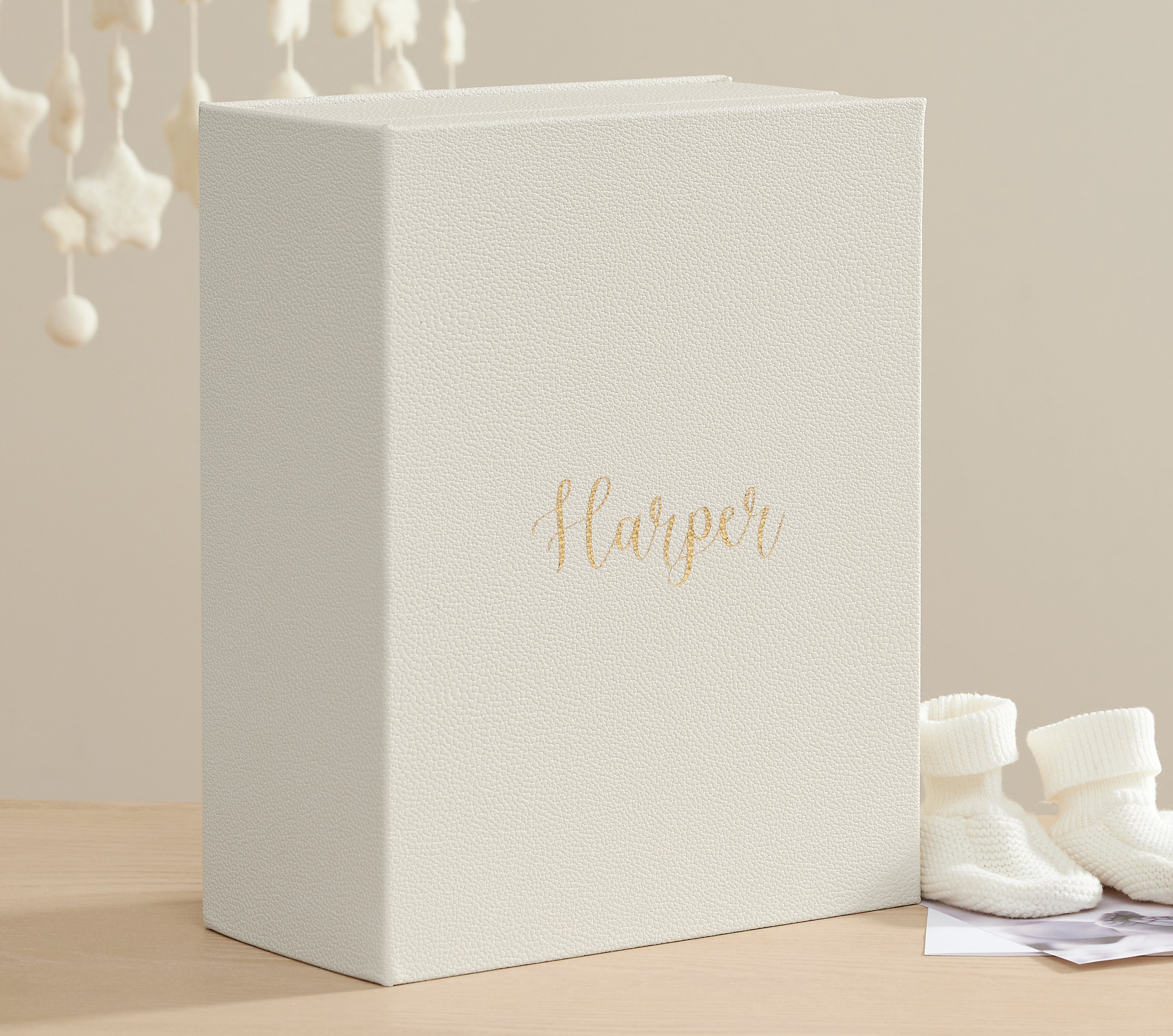 Closed three quarter view of a closed ivory shagreen vault personalized with harper with baby props