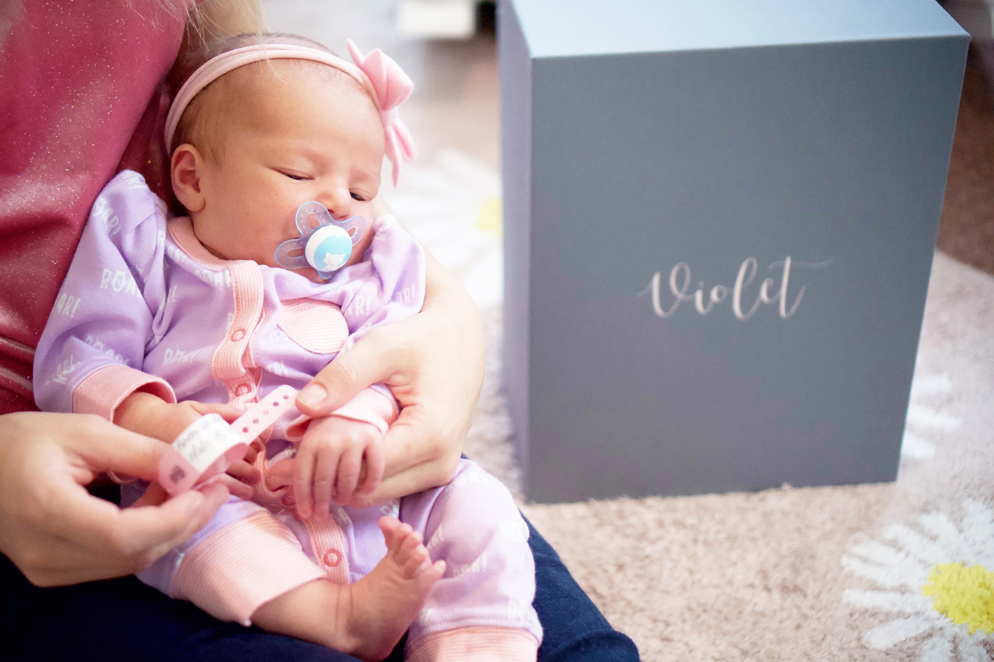 Newborn with bracelet and baby keepsake box saying Violet