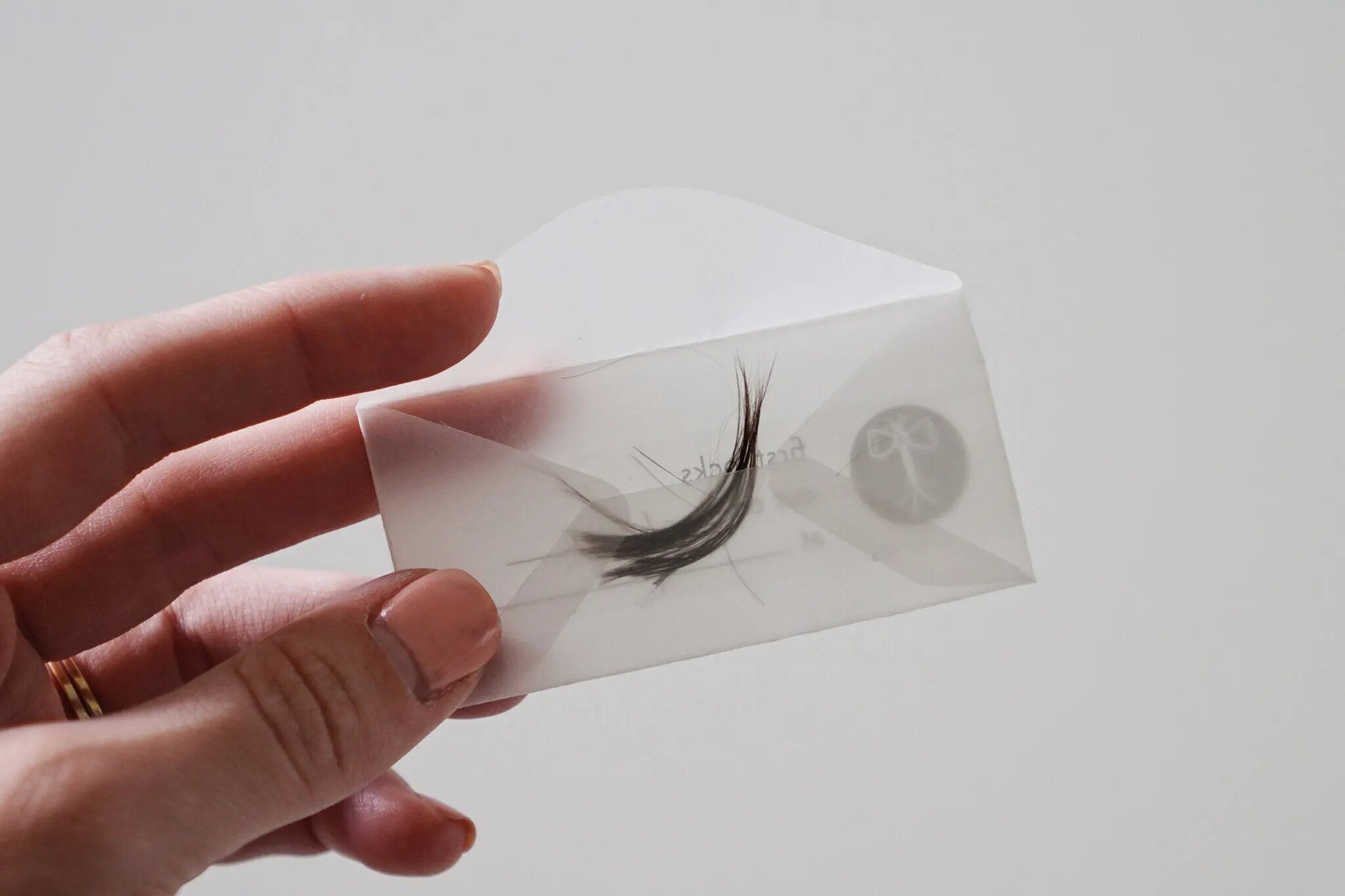 Someone holding a transparent envelope with a piece of hair.