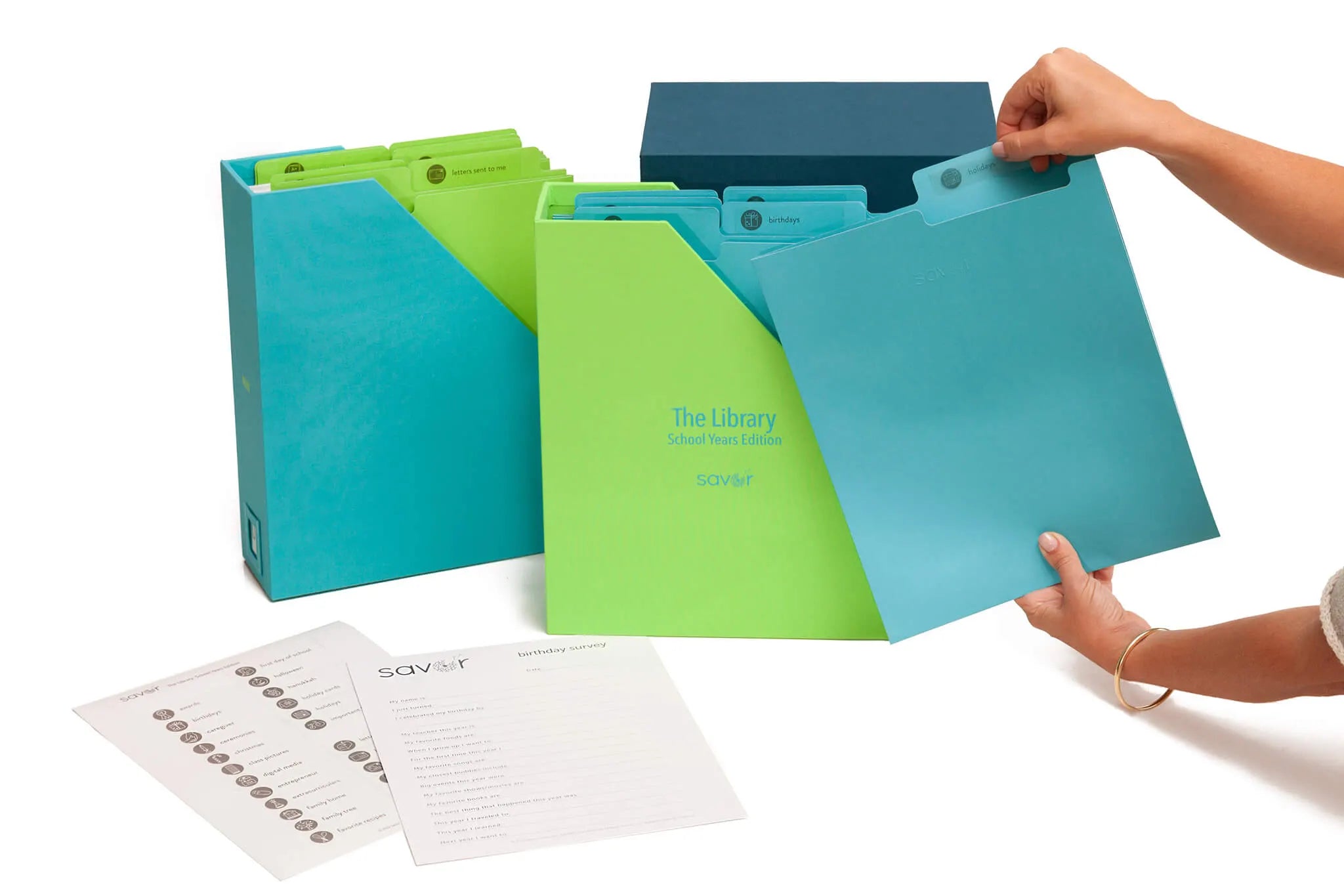 someone holding a folder and an open ocean school years deluxe keepsake box with a survey and label sheets