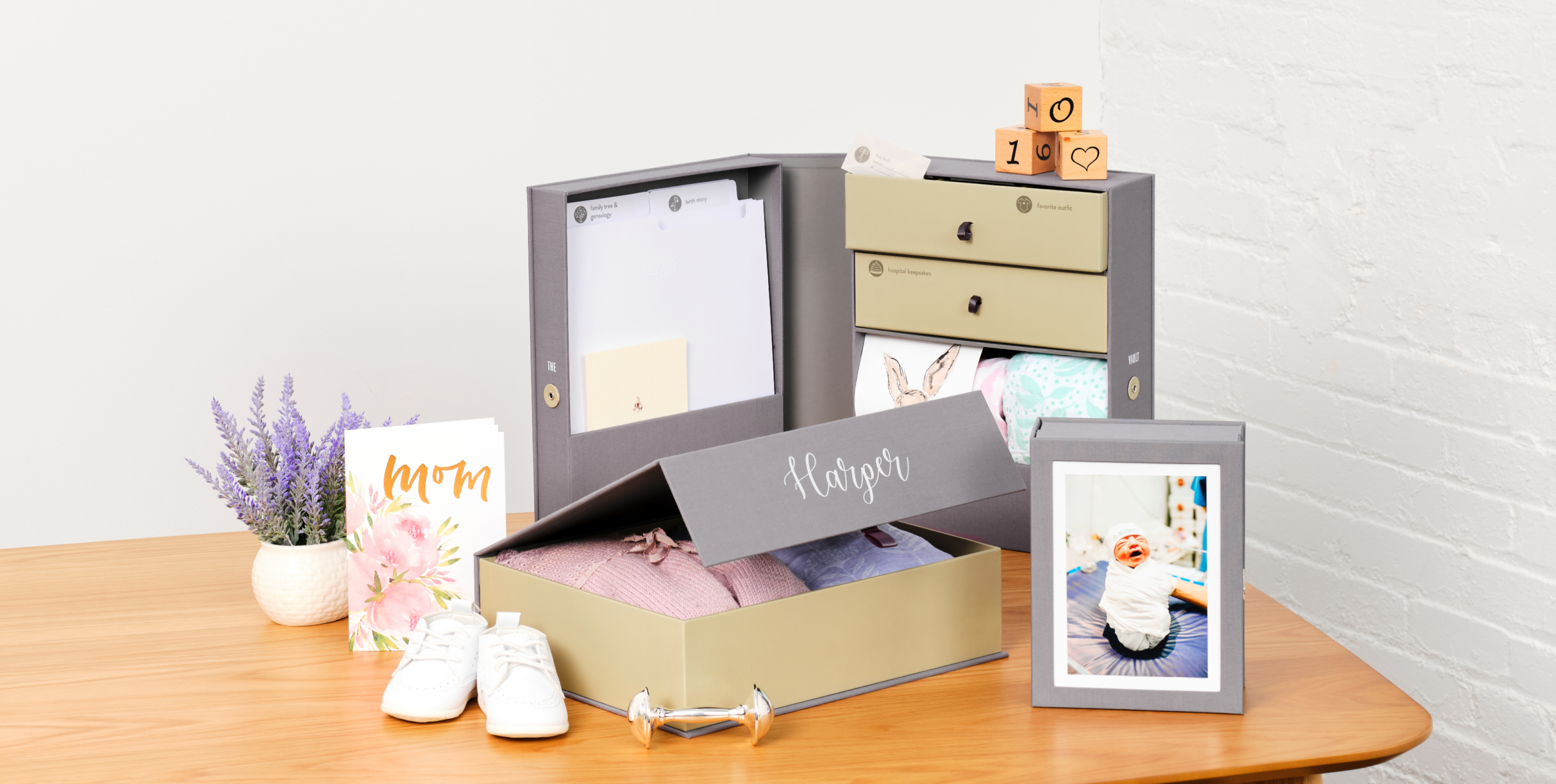 Grey organization set boxes for a newborn. Decorated with a picture of a baby, baby clothes and flowers.