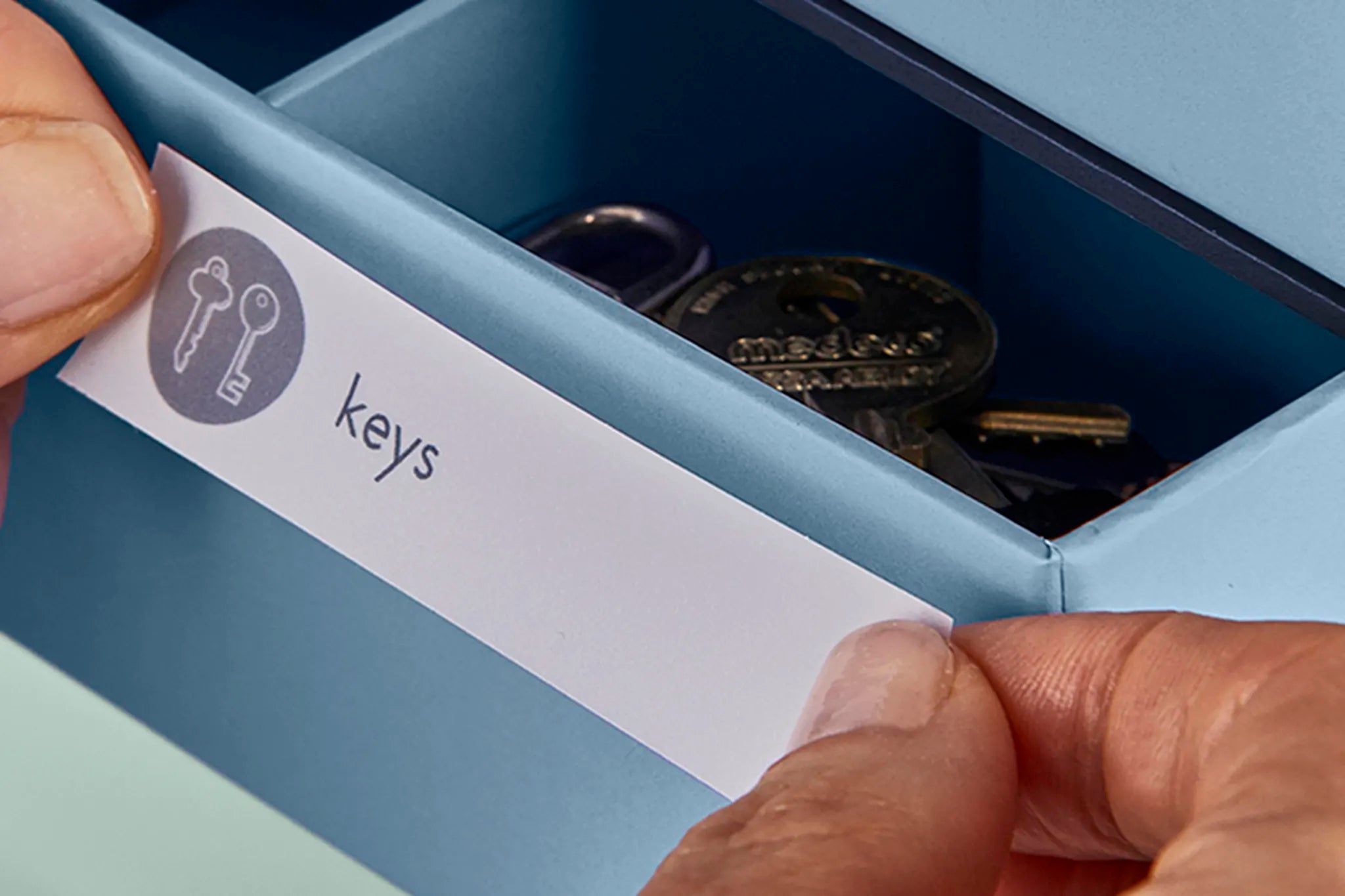 close up shot of an open something blue drawer and someone applying a label