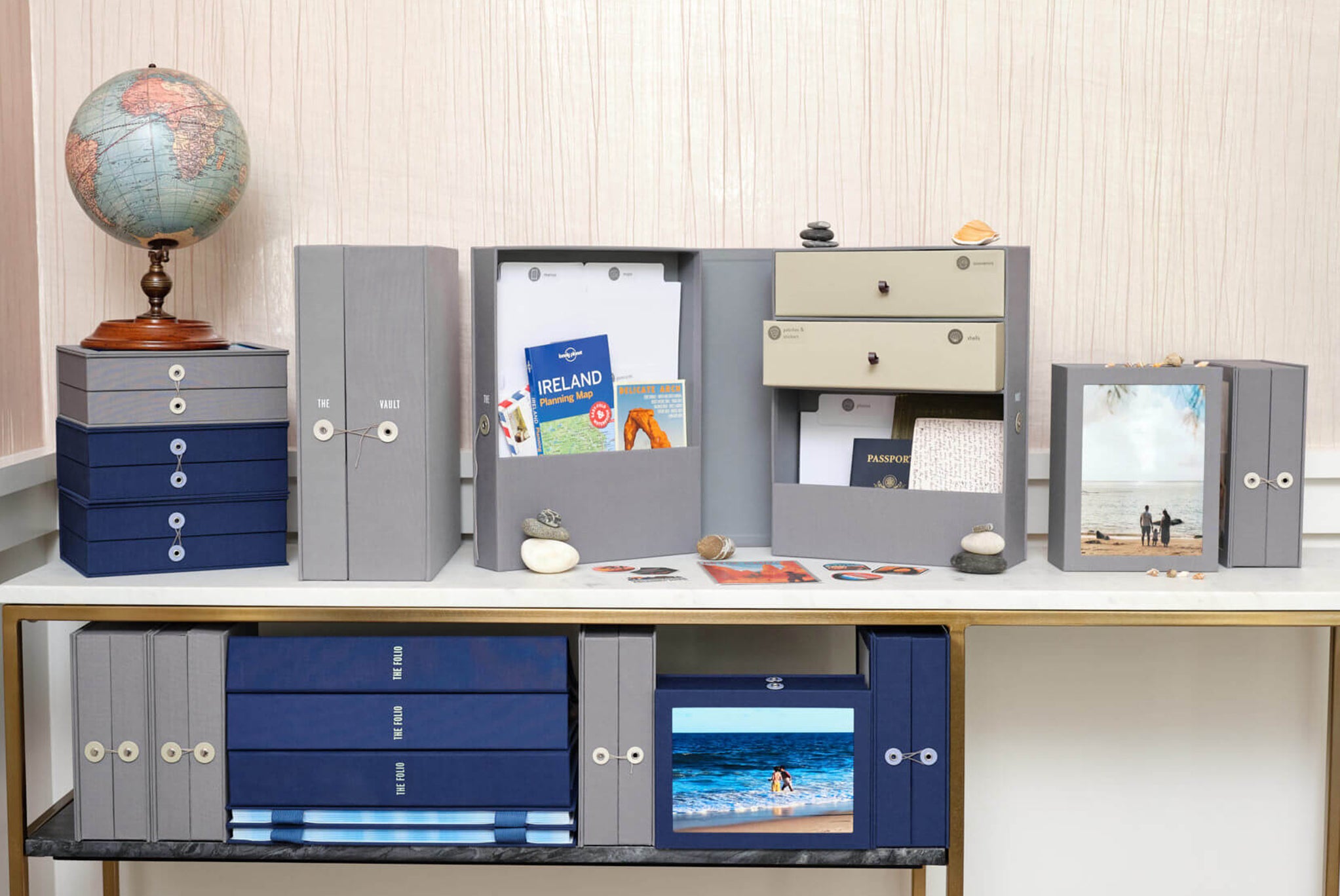 group shot of a shelf with several travel binders, travel vaults keepsake boxes and travel story boxes in slate and something blue