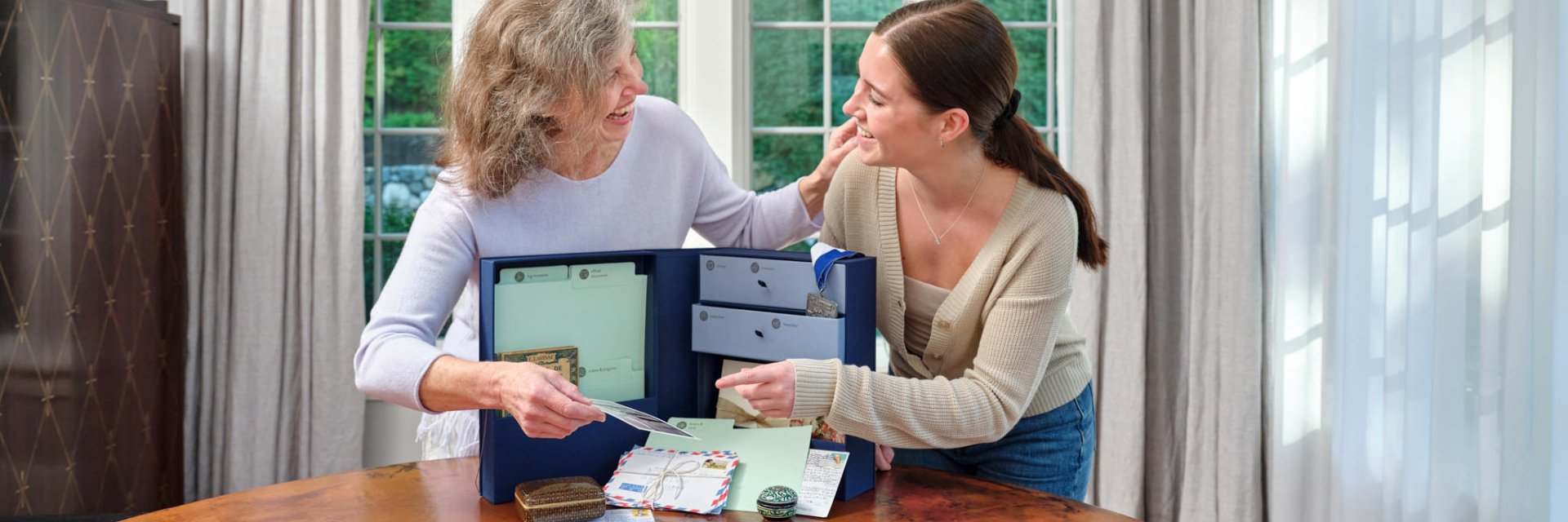 grandmother and granddaughter look at family heirlooms in family heritage keepsake box