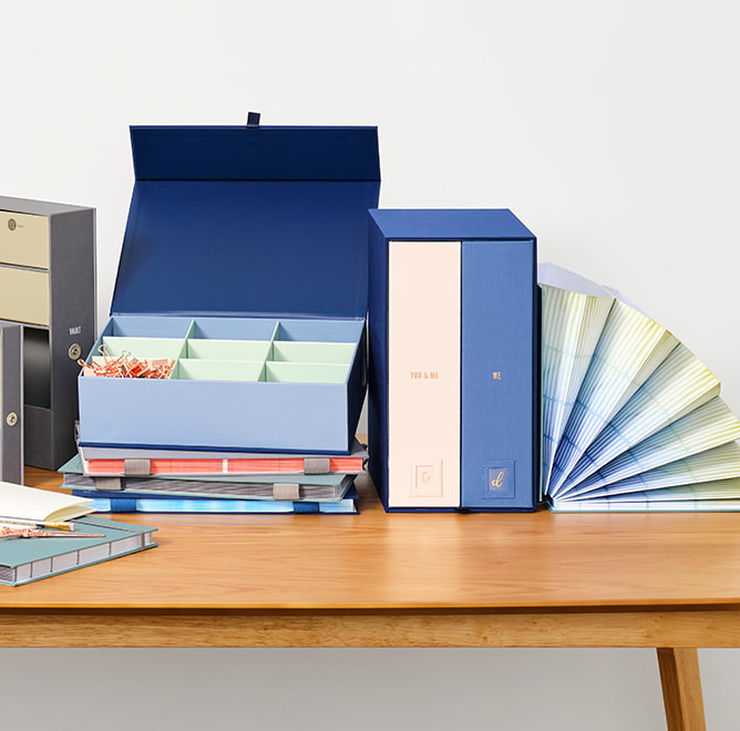 Blue organization boxes and document organizer folio open on a table.