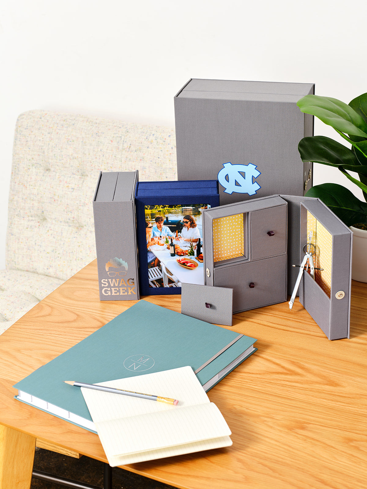 Savor organizers on top of a table: three story boxes, two closed and one open, a Vault with a logo and a fan folio closed with a pen and notebook on top