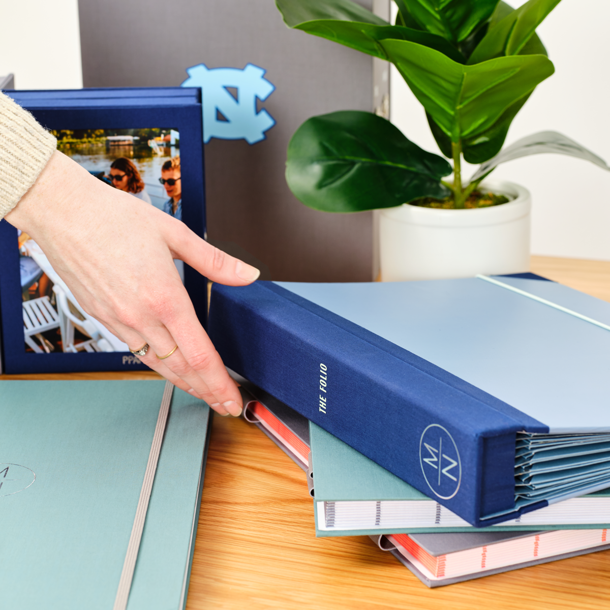 A woman’s hand putting a blue document organizer folio on a table.