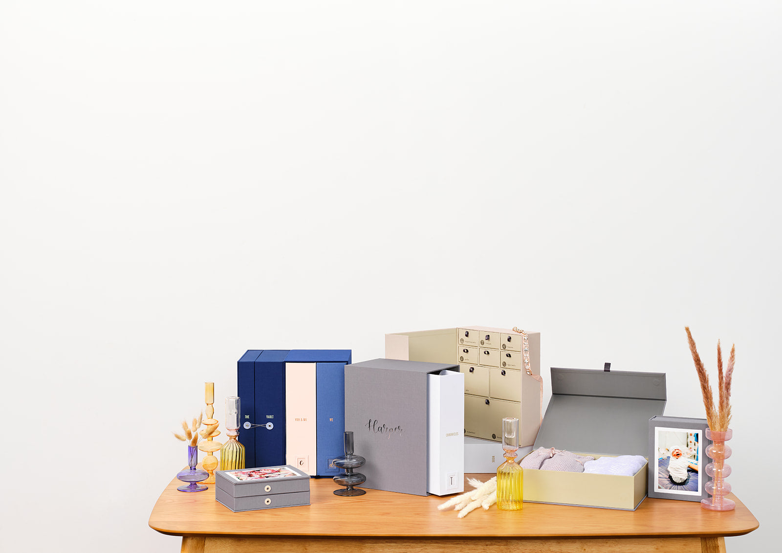 Savor keepsake boxes on top of a table: a Vault, a story box, a wedding deluxe keepsake box, a baby deluxe keepsake box, and an open overflow box