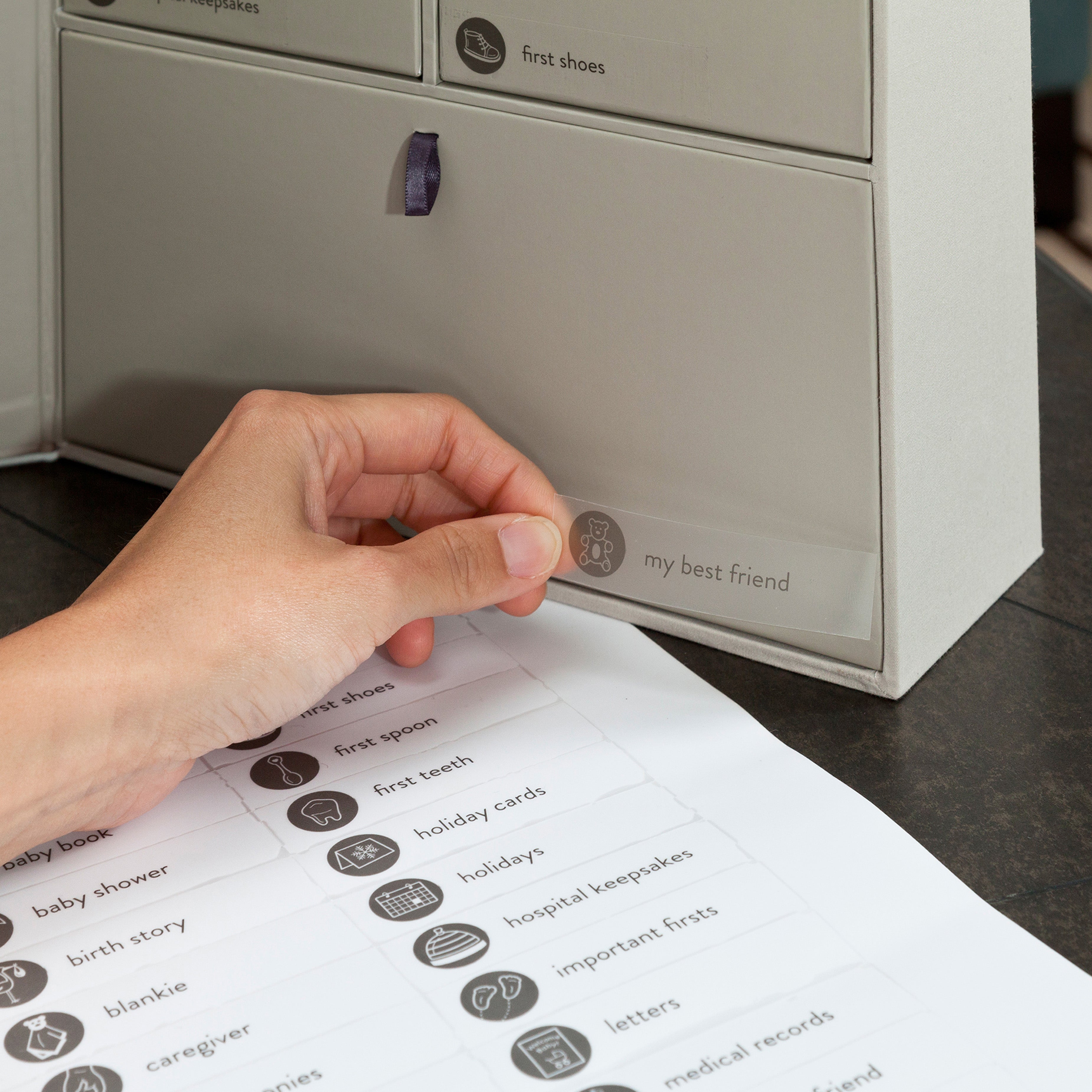 Someone applying a label on a beige drawer.