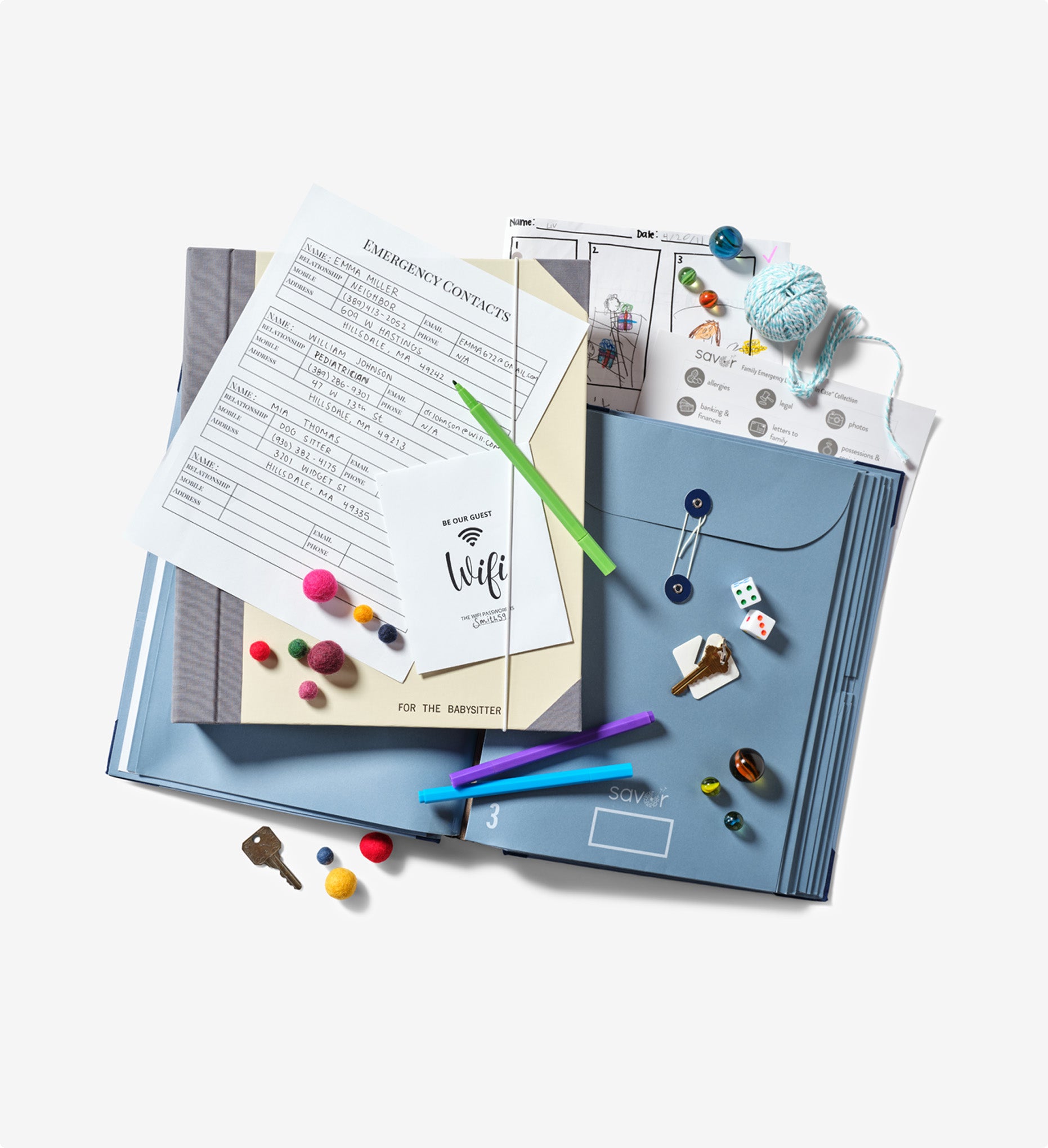 Savor babysitter binders: a blue one open and a slate one closed on top of it, with markers, dice and other items