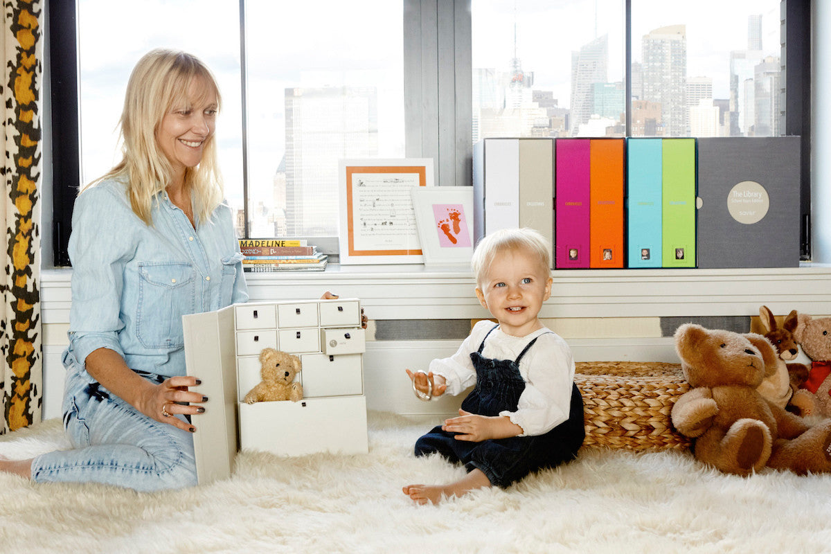 A mom holding a slate baby deluxe keepsake box and a baby