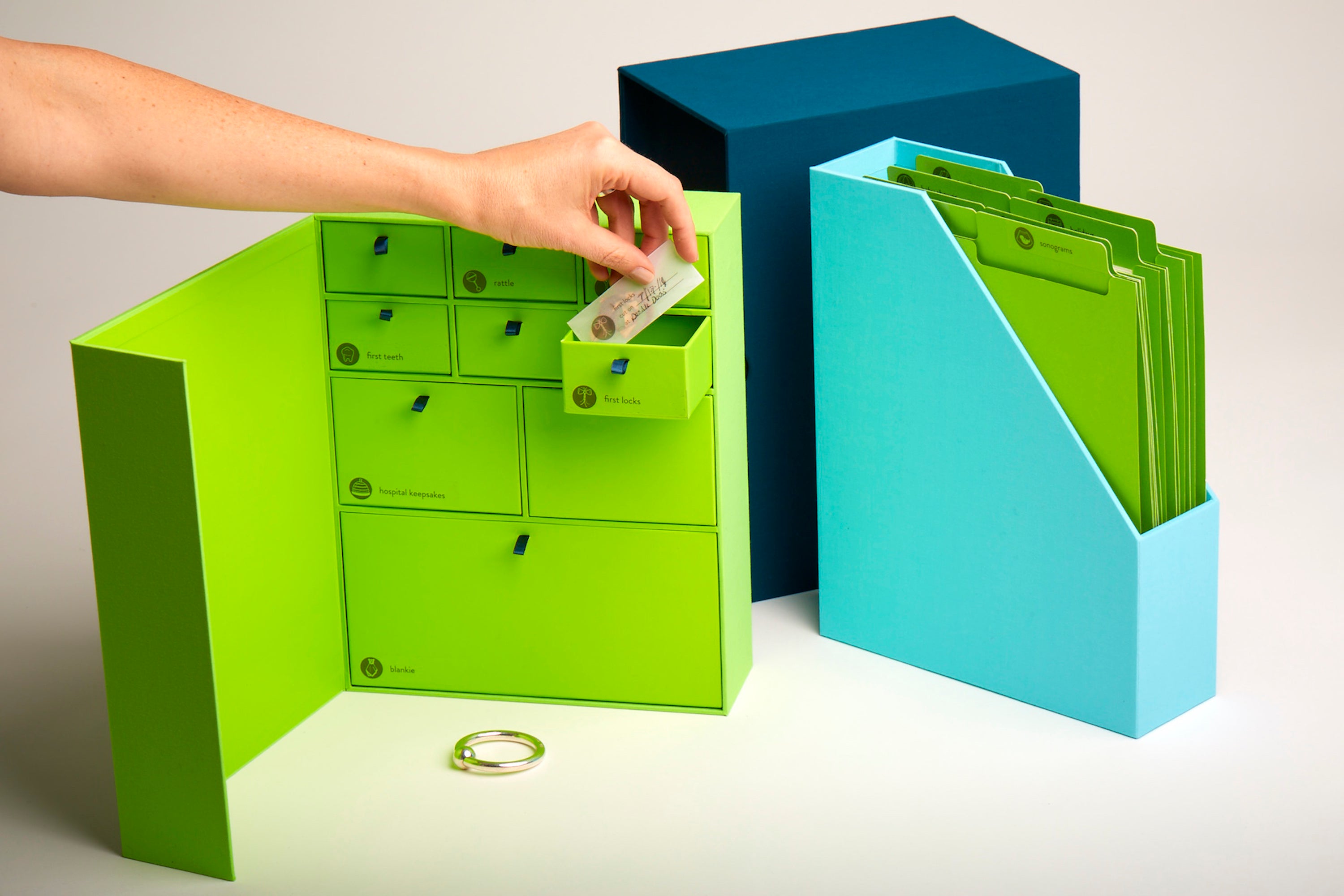 Someone putting a transparent envelope in a drawer of an ocean baby deluxe keepsake box.