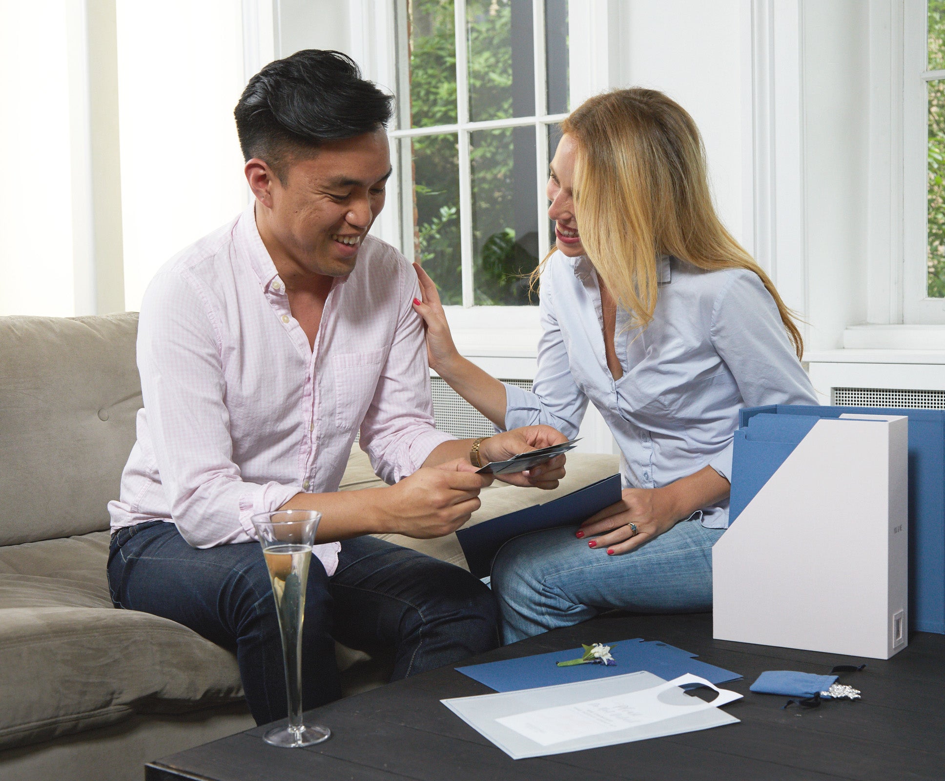 a couple in a living room with a glass of champagne and a something blue wedding deluxe keepsake box.