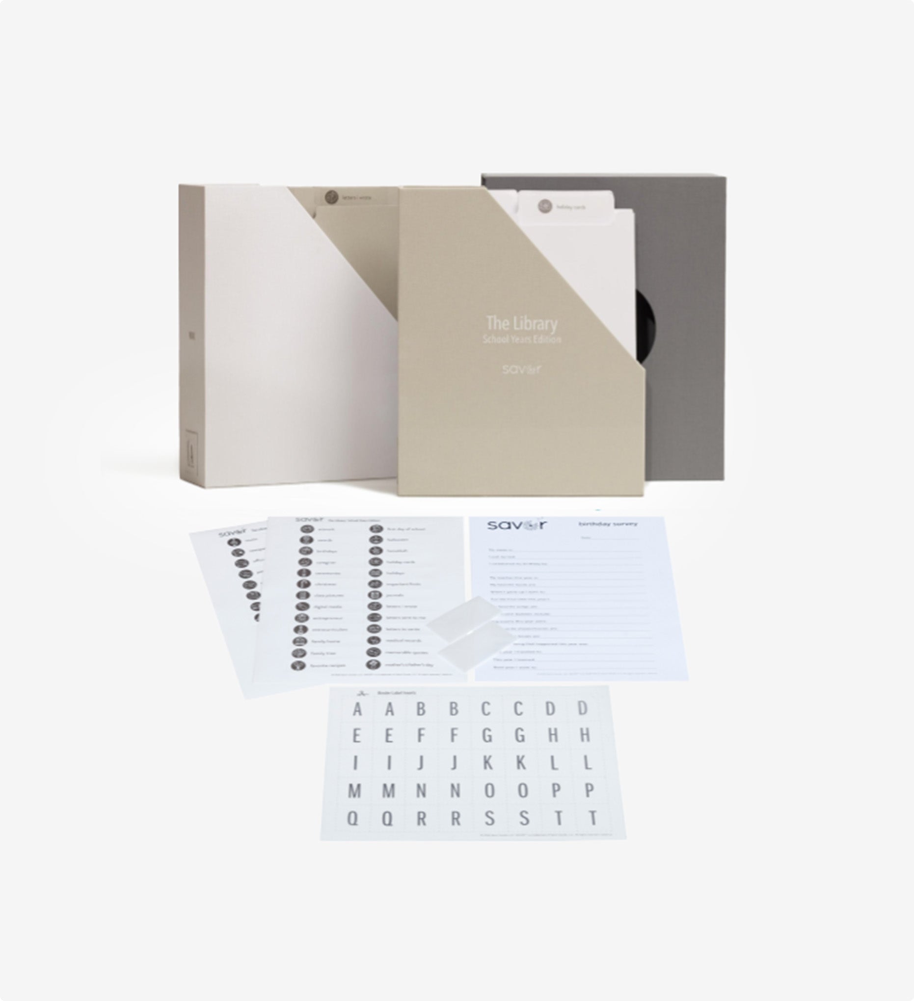 open slate school years deluxe keepsake box behind two label sheets, two transparent envelopes, a survey and a set of transparent letters.