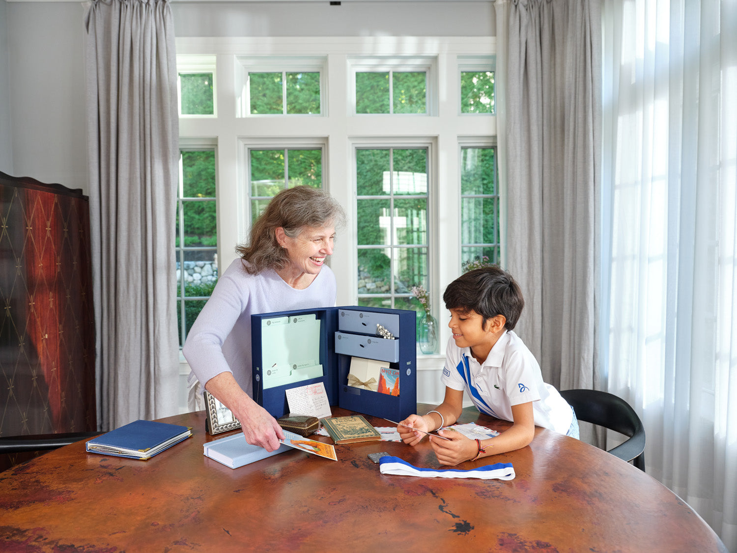a grandma and a grandson at a table with an open family heritage vault keepsake box in something blue.