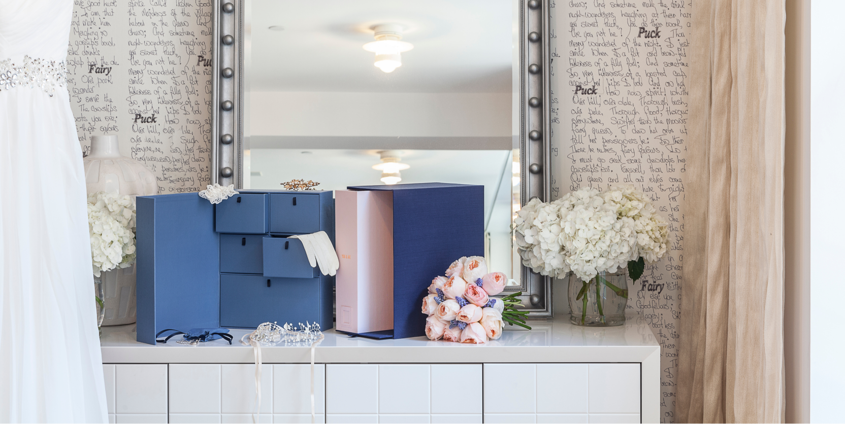 Blue organization boxes from wedding collection over a countertop decorated with flowers and bride items.