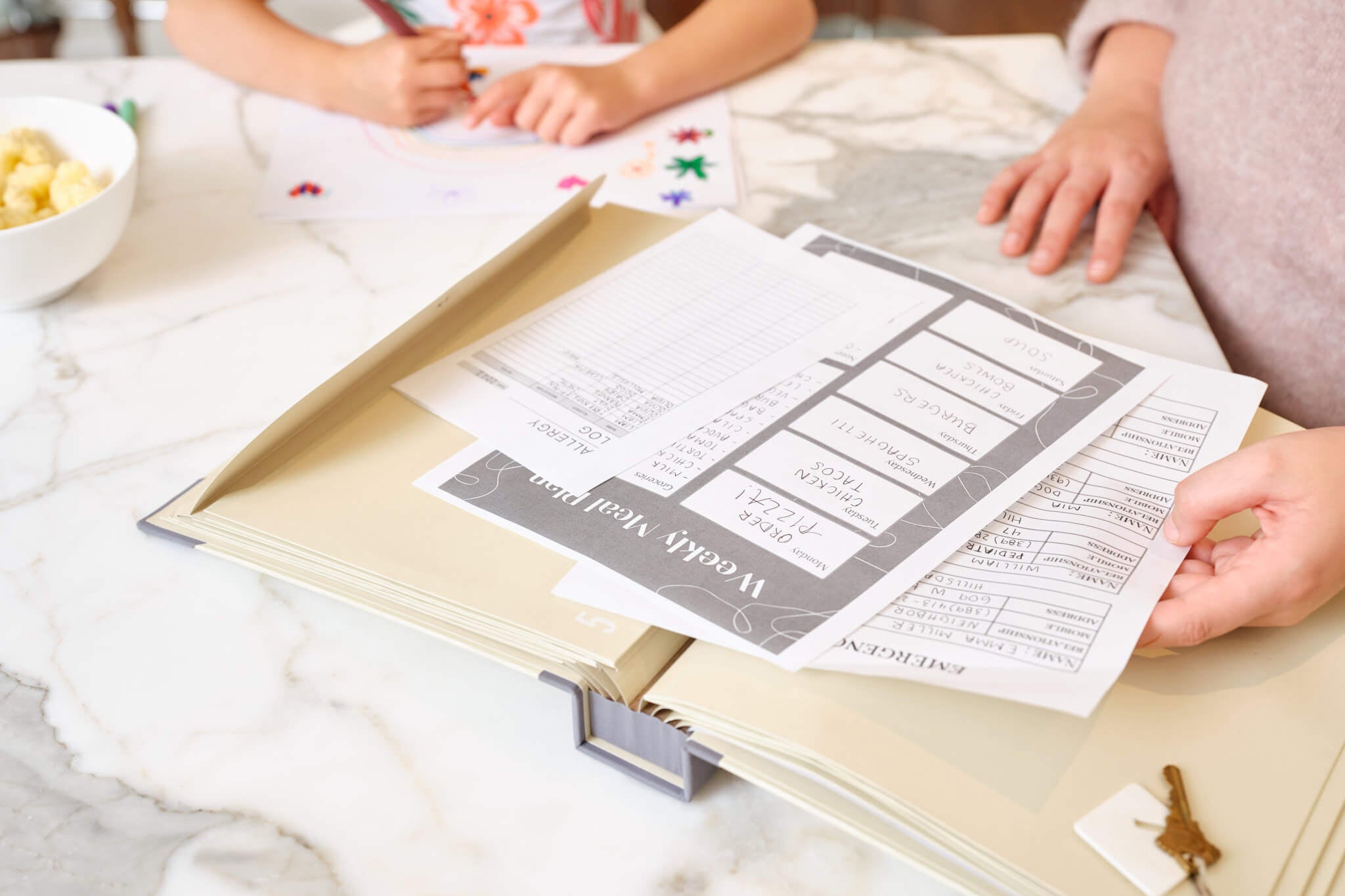 Savor babysitter binder open on table with partially visible worksheets, a woman and a child