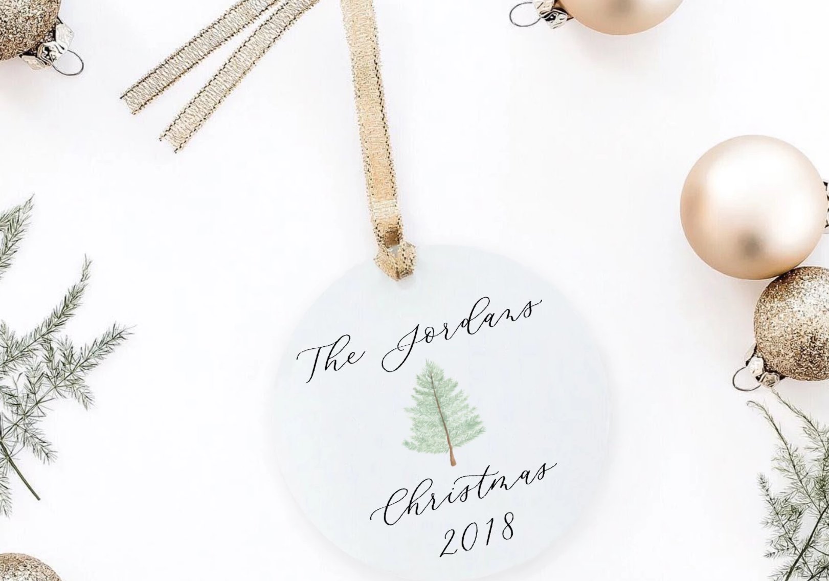 christmas ornament with a tree and a personalization in laura. Christmas props around it