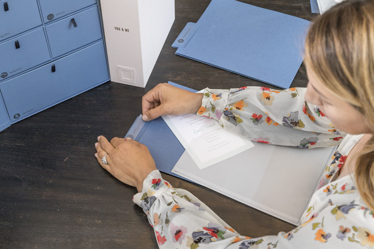 a woman applying a label on a something blue folder
