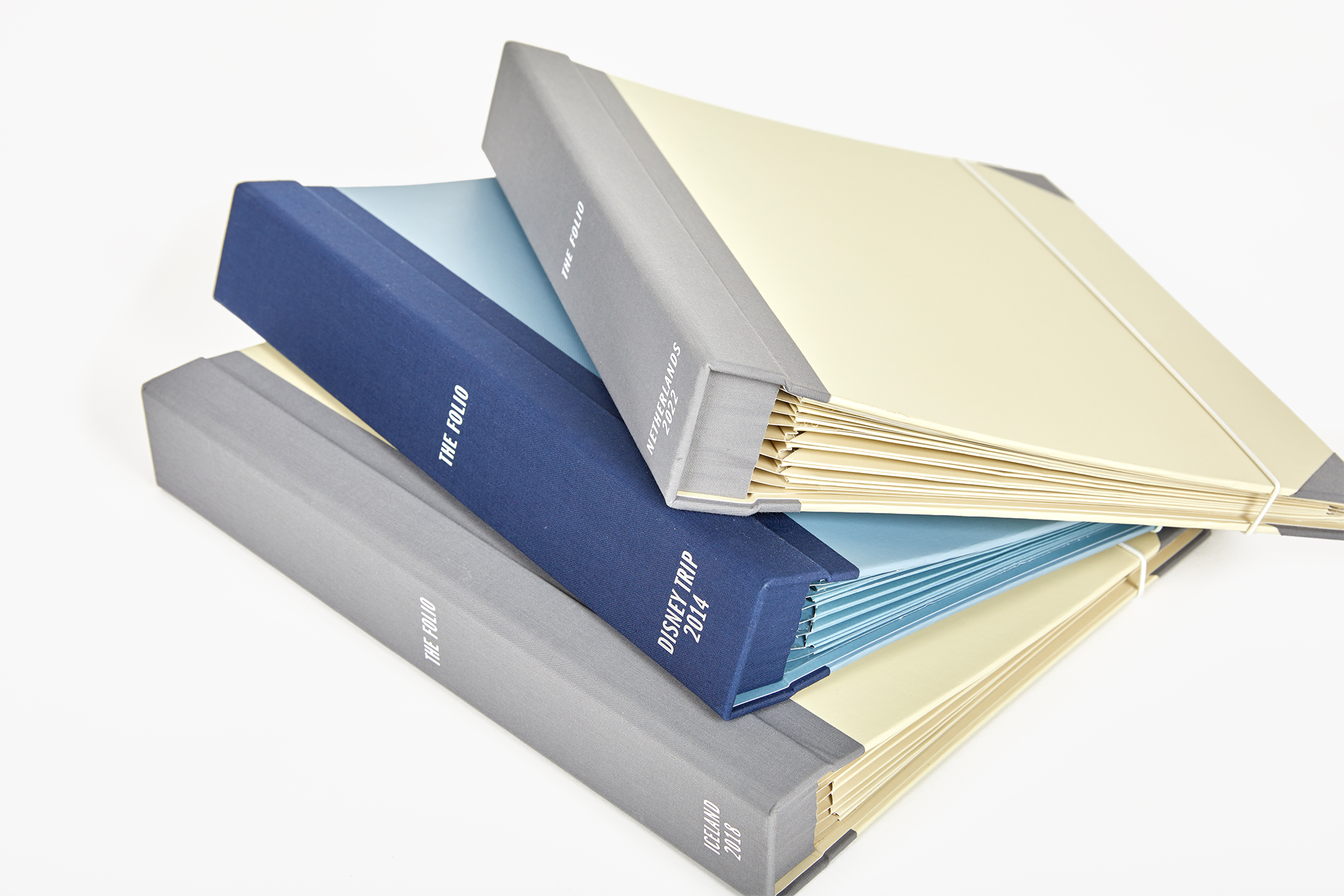 three piled up travel binders with personalizations. Two are slate and one is something blue